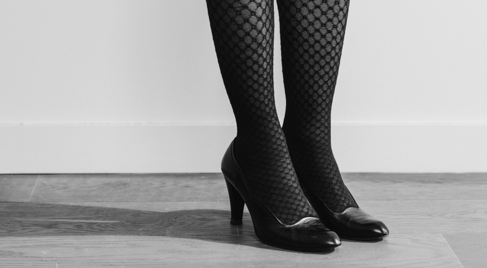A woman's legs wearing patterned stockings and high heels.