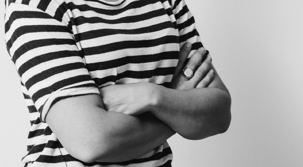cropped image of a woman wearing a stripey t-shirt with crossed arms.